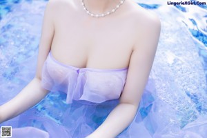 A woman in a purple dress sitting by a swimming pool.