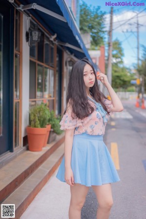 A young woman standing in front of a brick building.