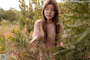 A naked woman standing in a field of tall grass.