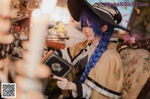 A woman dressed as a witch holding a stack of books.