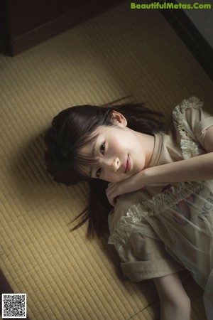 A woman sitting on a tatami mat holding a red rose.