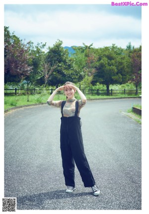 A woman sitting on a fence in front of a river.