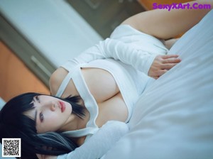A woman sitting on top of a bed with her legs crossed.