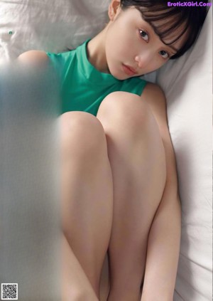 A woman laying on top of a bed next to a pillow.