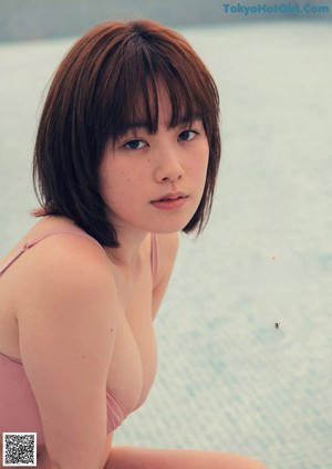 A woman in an orange bikini standing next to a pool table.