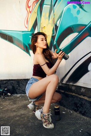 A woman leaning against a wall with graffiti on it.