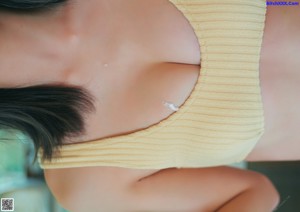 A woman in a nude bodysuit standing in front of a wall.