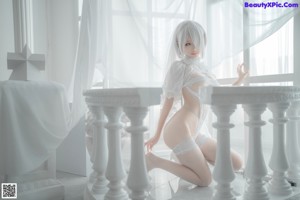 A woman in a white lingerie sitting on the floor.