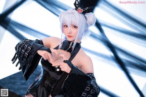 A woman in a black latex outfit sitting on a table.