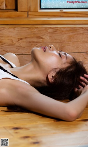 A woman sitting on the floor with her hand on her head.