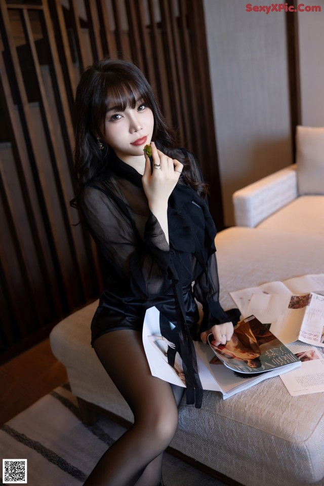 A woman sitting on a couch holding a magazine.