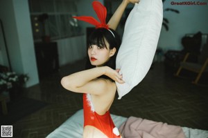 A woman in a red kimono sitting on the floor.