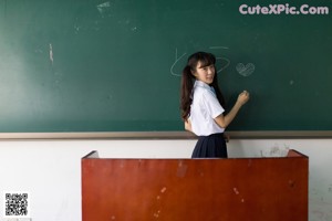 A woman sitting at a desk in a classroom.
