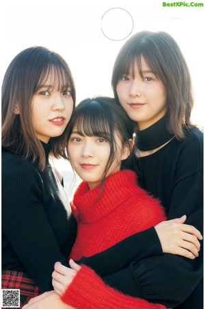 A group of three young women sitting next to each other.