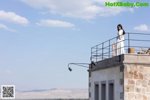 A woman in a black top and denim skirt posing on a set of stairs.