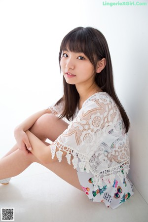 A woman in a white top and shorts posing for a picture.