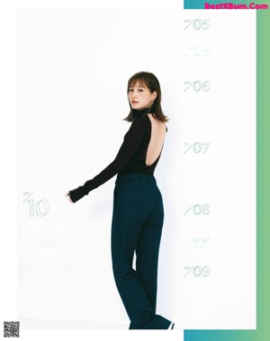 A woman in a black top and blue pants.