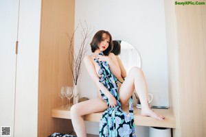 A woman standing on top of a bed next to a window.