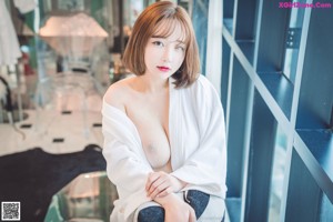 A woman in a black lingerie posing by a window.