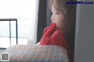 A woman in a red hoodie and yellow panties laying on a bed.