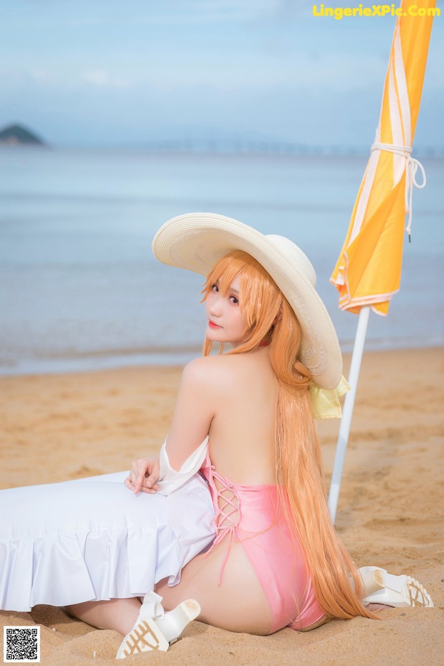 A woman in a pink bikini sitting on the beach.