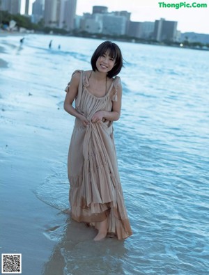 A woman in a black bikini standing on a beach.