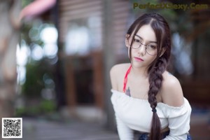 A woman wearing glasses and a white top posing for a picture.
