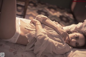 A woman sitting on a bed with her legs crossed.
