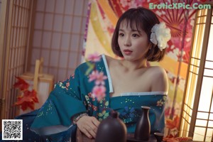 A woman in a blue kimono sitting at a table.