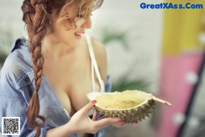 A woman sitting on the floor next to a bunch of durians.