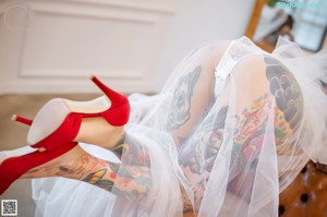 A woman with tattoos sitting on a couch wearing a wedding dress.