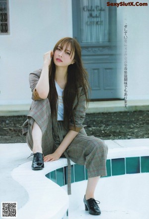 A woman sitting on top of a bed next to a window.