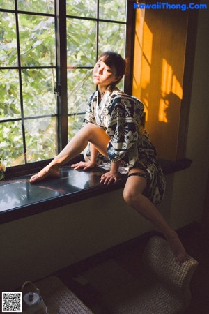 A woman sitting on a chair in front of a window.